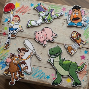 May include: A collection of embroidered patches featuring characters from the animated film Toy Story. The patches include Jessie, Buzz Lightyear, Mr. Potato Head, Hamm, Slinky Dog, Woody, Bullseye, and Rex. The patches are colorful and detailed.