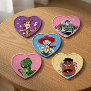 Può includere: Cinque toppe ricamate a forma di cuore con i personaggi di Toy Story. La toppa viola mostra Woody, quella rosa Buzz Lightyear, quella blu Jessie, quella rosa chiaro Rex e quella gialla Mr. Potato Head, decorate con piccole stelle gialle.