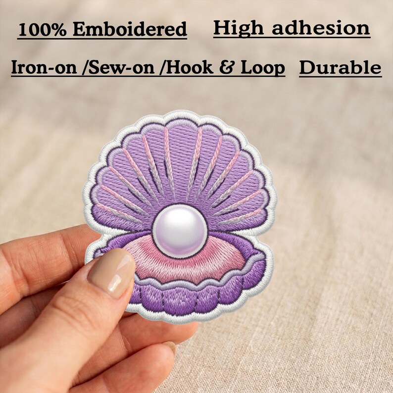 May include: An embroidered patch shaped like an open purple seashell containing a white pearl. The text reads 100% Emboidered, High adhesion, Iron-on /Sew-on /Hook & Loop, and Durable. The patch features shades of purple and pink thread.