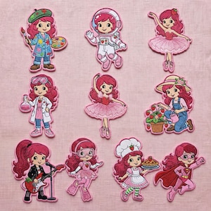 Peut inclure: Collection de patchs brodés représentant un personnage de dessin animé aux cheveux roses dans diverses professions et costumes. Les patchs incluent un astronaute, une ballerine, une scientifique, un chef, une super-héroïne et une artiste.
