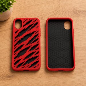May include: Two rectangular smartphone cases with red borders. The left case features a black background with a red diagonal slash pattern. The right case has a black interior with a textured hexagonal pattern and a smooth red outer frame.