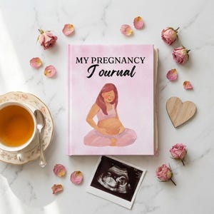 May include: A light pink hardcover journal titled MY PREGNANCY Journal with an illustration of a pregnant person in a seated position. The journal is surrounded by dried pink rose petals, a wooden heart, a teacup, and a black and white ultrasound scan.