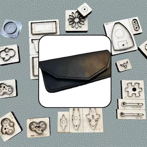 Peut inclure: Un portefeuille en cuir noir de style enveloppe avec un rabat pointu et des coutures visibles, entouré de divers emporte-pièces métalliques sur blocs de bois, incluant des formes comme une fleur, une pièce de puzzle et des formes géométriques.