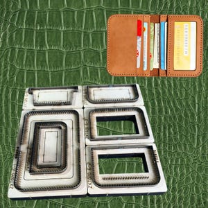 Puede incluir: Una cartera de cuero marrón con múltiples ranuras para tarjetas y una ventana de identificación transparente, mostrada abierta. Debajo se disponen varias herramientas metálicas troqueladas para artesanía en cuero. Las herramientas son rectangulares y tienen un filo.