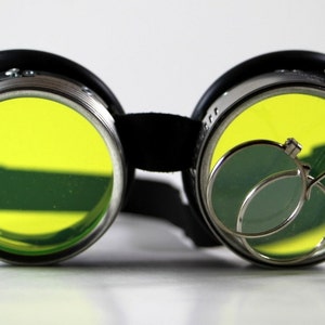 May include: Black steampunk goggles with yellow lenses and a silver magnifying glass attachment.