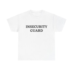 Könnte beinhalten: Ein weißes kurzärmeliges T-Shirt mit dem Text INSECURITY GUARD, der in schwarzen Großbuchstaben mittig auf der Brust aufgedruckt ist. Das Kleidungsstück hat einen Rundhalsausschnitt und eine Standardpassform aus schlichtem weißem Stoff.