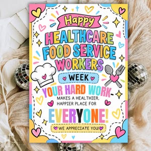 Op de afbeelding: Een kleurrijk rechthoekig bord met de tekst Happy Healthcare Food Service Workers Week. Het bevat een witte koksmuts, een lepel, een vork en hartjes. De tekst luidt Your hard work makes a healthier, happier place for everyone!