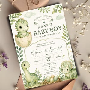 Può includere: Un invito per baby shower con illustrazioni ad acquerello di dinosauri verdi, un nido con uova e foglie. Il testo recita: Something wonderful is on the way! A sweet baby boy is almost here. Please join us for a baby shower honoring Olivia & Daniel, Saturday, October 12 at 3:00 PM, 456 Jurassic Way, Dino Valley, CO 80220.