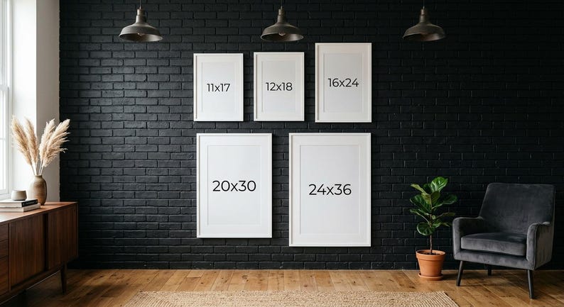 May include: Five white framed art prints of varying sizes are displayed on a black brick wall. The sizes are 11x17 inches, 12x18 inches, 16x24 inches, 20x30 inches, and 24x36 inches. The room has a modern aesthetic with a wooden floor and a dark gray armchair.