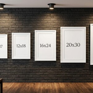 May include: Five white framed art prints of varying sizes are displayed on a dark brick wall. The sizes are labeled as 11x17 inches, 12x18 inches, 16x24 inches, 20x30 inches, and 24x36 inches. The room has a modern aesthetic with a wooden floor.
