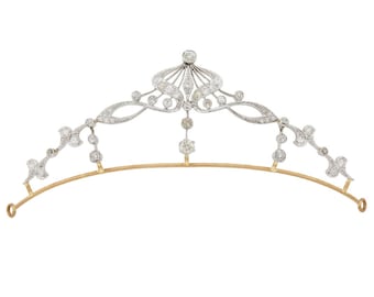 May include: A delicate silver tiara with a floral design and a row of sparkling diamonds. The tiara is set on a gold band and has a delicate, feminine look.
