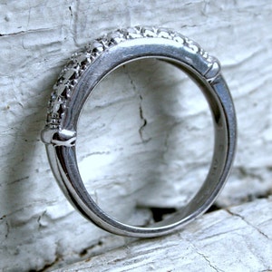 May include: A silver band ring with small diamonds set in the band.