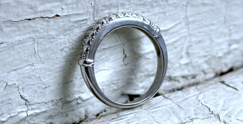 May include: A silver band ring with small diamonds set in the band.