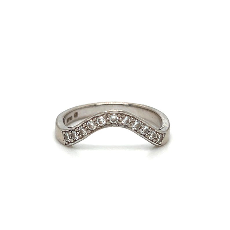 Puede incluir: Un anillo de plata con una banda curva y una fila de peque&ntilde;as piedras transparentes.