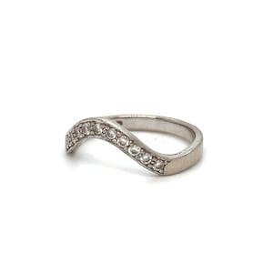 Puede incluir: Un anillo de plata con una banda ondulada y una fila de piedras de circonita c&uacute;bica transparentes.