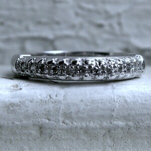 May include: A silver band ring with a row of small, clear gemstones.