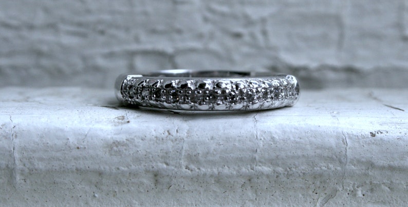 May include: A silver band ring with a row of small, clear gemstones.