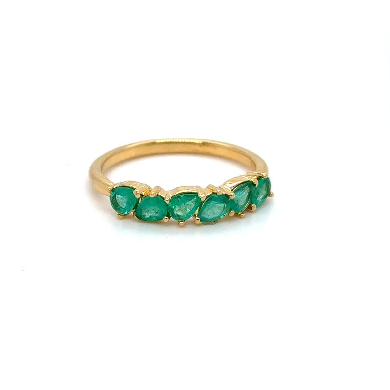 May include: A gold band ring with a row of emerald green gemstones.