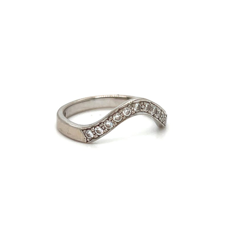 Puede incluir: Un anillo de plata con una banda ondulada y peque&ntilde;as piedras transparentes engastadas en la banda.