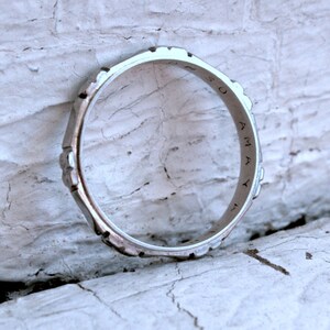 May include: A silver ring with a textured design and the word "OMAY" inscribed on the band.