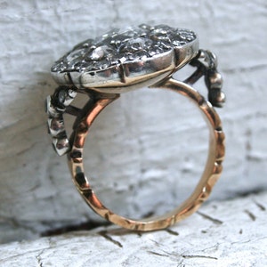 May include: A silver ring with a large, round, faceted gemstone set in a bezel setting. The ring band is gold and has a textured design.
