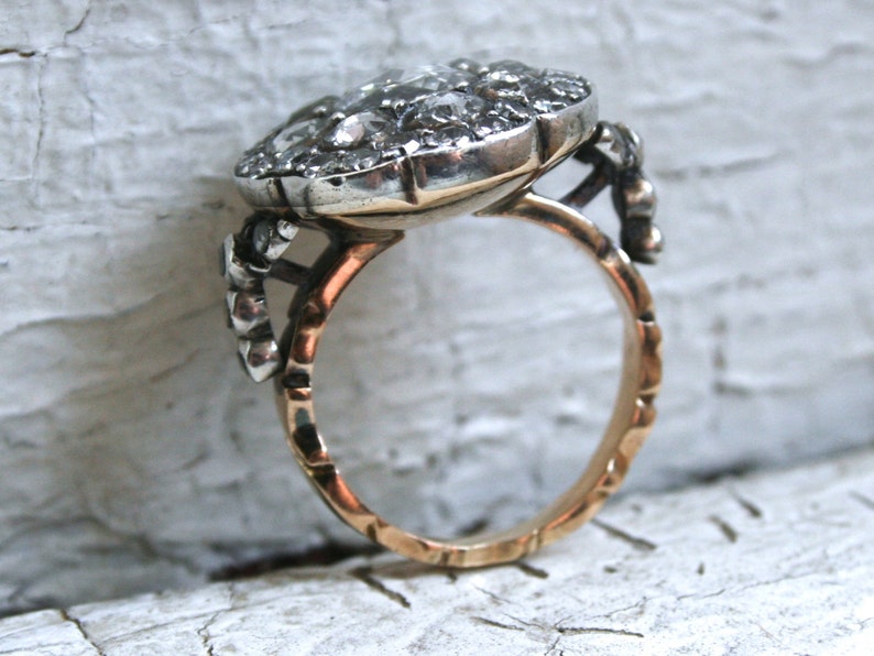 May include: A silver ring with a large, round, faceted gemstone set in a bezel setting. The ring band is gold and has a textured design.