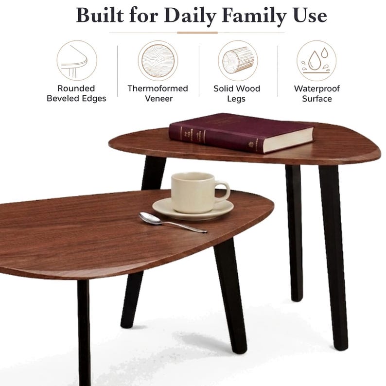 May include: Two nesting tables with dark wood-grain tops and black legs. The text Built for Daily Family Use appears above icons labeled Rounded Beveled Edges, Thermoformed Veneer, Solid Wood Legs, and Waterproof Surface. A book, cup, and spoon sit on top.
