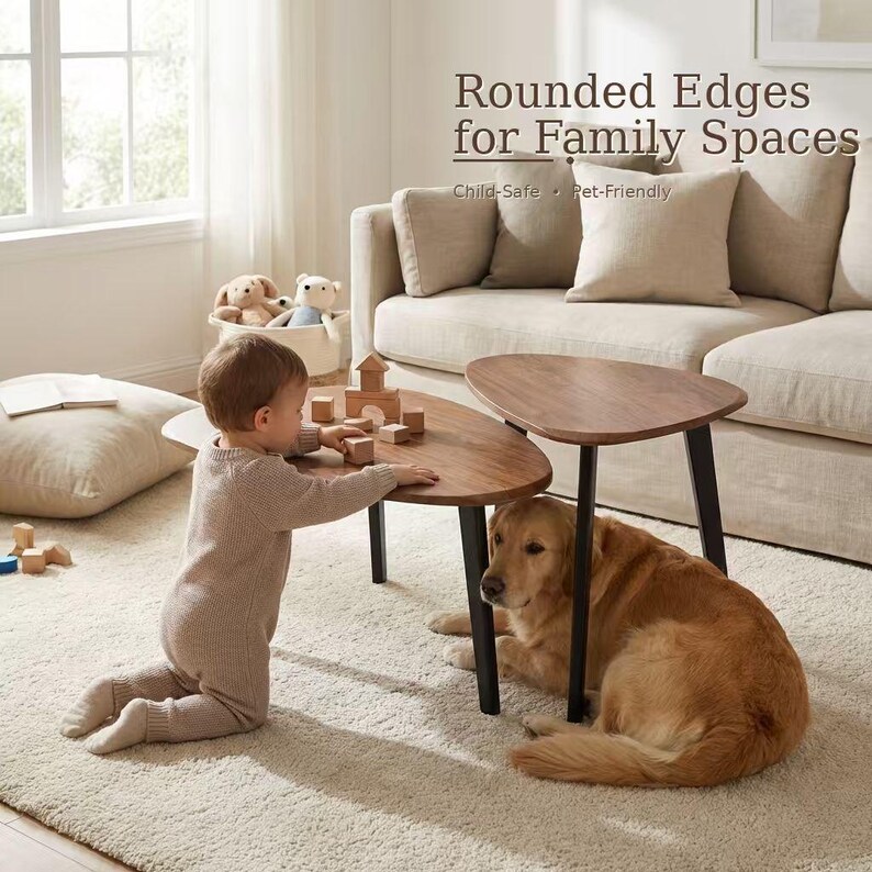May include: Two nesting coffee tables with dark wood triangular tops and black legs. The text reads: Rounded Edges for Family Spaces, Child-Safe, Pet-Friendly. The tables are positioned on a light-colored rug in a living room setting.