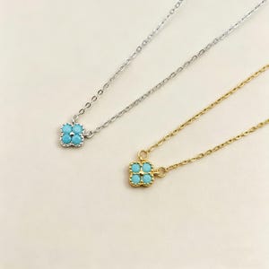 May include: Two delicate necklaces with four-leaf clover pendants. One necklace is silver-toned, the other gold-toned. Each pendant features four turquoise-colored stones. The chains are fine and the pendants are centered.