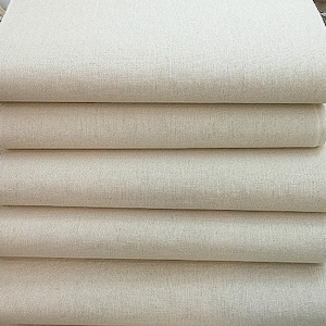 May include: A stack of off-white fabric rolls. The fabric has a woven texture and appears to be a natural fiber. The rolls are neatly stacked, showcasing the material's thickness and potential for various uses.