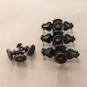 May include: Four antique brass cabinet knobs with a decorative design and a round knob. Three smaller brass knobs with a screw.
