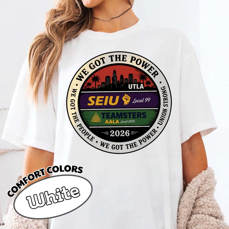 May include: White t-shirt with a circular graphic featuring the text "WE GOT THE POWER" and "UTLA". The graphic includes a cityscape, palm trees, and the text "SEIU Local 99" and "TEAMSTERS AALA Local 2010". The shirt also has the text "COMFORT COLORS" and "White".