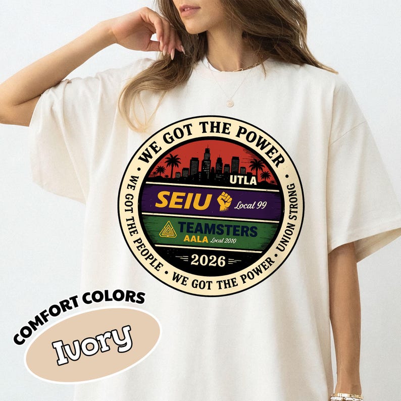May include: Ivory-colored t-shirt with a circular graphic featuring text: "WE GOT THE POWER," "SEIU," "TEAMSTERS," and "2026." The graphic includes a cityscape silhouette and palm trees. The shirt is labeled "COMFORT COLORS."