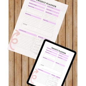 May include: A project planner and a digital tablet displaying a project planner, both on a wooden surface. The planner includes sections for project details, objectives, resources, and a timeline. The text "Project Planner" is visible.