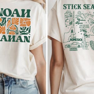 Może przedstawiać: Kremowa koszulka z zielono-pomarańczowym kwiatowym wzorem i napisem "NOAH AHAN" w kolorze zielonym. Tył koszulki zdobi zielona grafika z napisami, w tym "STICK SEA", "HOMESICK" i "GROWING SIDEWAYS".