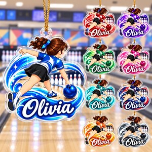 May include: A clear acrylic hanging ornament featuring a cartoon illustration of a person bowling with a blue ball. The design includes swirling graphic elements, bowling pins, and the name Olivia in white script. The ornament hangs from a gold cord.
