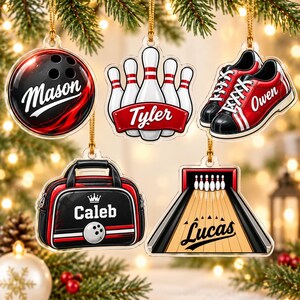 May include: Five acrylic bowling-themed Christmas ornaments hanging by gold strings. The ornaments feature a red and black bowling ball with the name Mason, white bowling pins with the name Tyler, red and black bowling shoes with the name Owen, a black bowling bag with the name Caleb, and a bowling lane with the name Lucas.
