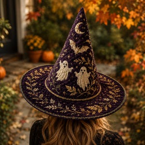 May include: A quilted purple witch hat featuring gold embroidered details including two white ghosts, a bat, a crescent moon, stars, and leafy vine patterns along the wide brim. The fabric has a textured, stitched finish throughout the conical crown.