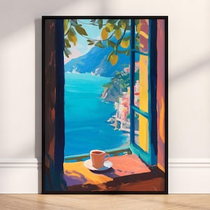 May include: A framed art print showing a coastal scene through a window. The artwork features a vibrant blue sea, a mountain range, and colourful buildings. A cup of coffee sits on a saucer on the windowsill, with lemon tree branches overhead.