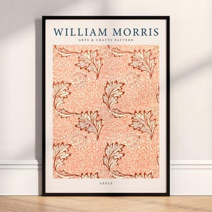 Può includere: Stampa artistica incorniciata con un motivo William Morris Arts & Crafts. Il design presenta un motivo ripetuto di foglie stilizzate ed elementi floreali nei toni del corallo, marrone e crema, su sfondo corallo. La stampa è etichettata "APPLE".