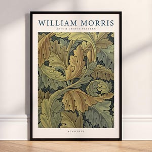 May include: A framed art print featuring a William Morris Arts & Crafts pattern. The design showcases stylized acanthus leaves in shades of gold, green, and brown against a dark background. The print is enclosed in a black frame, with the text "WILLIAM MORRIS" at the top.
