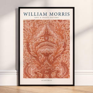 May include: Framed art print featuring a detailed, repeating pattern in shades of orange and cream. The print is labeled "WILLIAM MORRIS ARTS & CRAFTS PATTERN" and "ACANTHUS" in navy blue text. The artwork is displayed in a black frame.