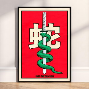 May include: Framed art print featuring a green snake coiled around a katana blade against a red background. The Japanese characters and the text "SHED THE OLD SKIN" are also visible. The artwork is in a black frame.