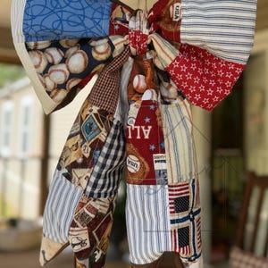 May include: A white ceramic mug with a black handle and the text "But First, Coffee" in a bold, black font. The mug is set against a blurred background, suggesting a cozy setting.