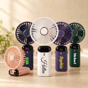May include: A collection of portable personal fans in various colors, including pink, white, navy, purple, and green. Each fan has a digital display and a name printed on the base. The fans are designed for personal cooling.