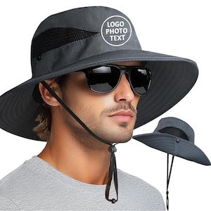 May include: A grey sun hat with a wide brim and a black mesh panel. The hat has a chin strap and a white circular logo that says "LOGO PHOTO TEXT". The person in the image is wearing black sunglasses.