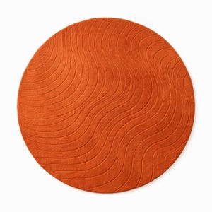 May include: A round, orange rug with a wave pattern. The rug is a solid color and has a textured surface. The design features curved lines that create a flowing, organic look. This rug is suitable for living rooms, bedrooms, or entryways.