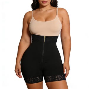 Könnte beinhalten: Schwarze Shapewear-Shorts mit hohem Bund und Spitzenbesatz am Saum. Die Shorts haben ein Design mit hohem Bund, ein schwarzes Spitzenband und einen goldenen Reißverschluss. Das Model trägt ein beiges Camisole.