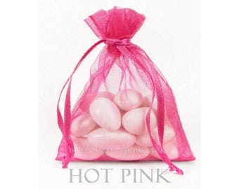 May include: A hot pink sheer organza drawstring pouch filled with several smooth, light pink oval-shaped candies. The bag is made of a translucent, fine-mesh fabric and is cinched at the top with matching hot pink ribbon ties.