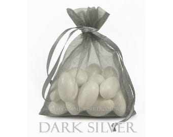 May include: A dark silver sheer organza drawstring pouch filled with multiple smooth, white, oval-shaped candies. The bag features a translucent fabric texture and is tied at the top with matching ribbons. Text on the bag reads ETSY.COM/SHOP/SHEERCOLORS and DARK SILVER.